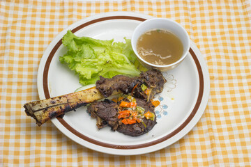 Iga Bakar or Roasted Ribs served with chili sauce and soup on plate