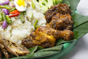 selective focus of Ayam bakar or grilled chicken served with nasi liwet A traditional Sundanese rice dish of white rice cooked with spices and topped