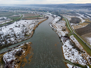 Aerial view. Flowing river seen from above. A view of the mountains on the horizon. Snow, sun, landscape, nature, park.