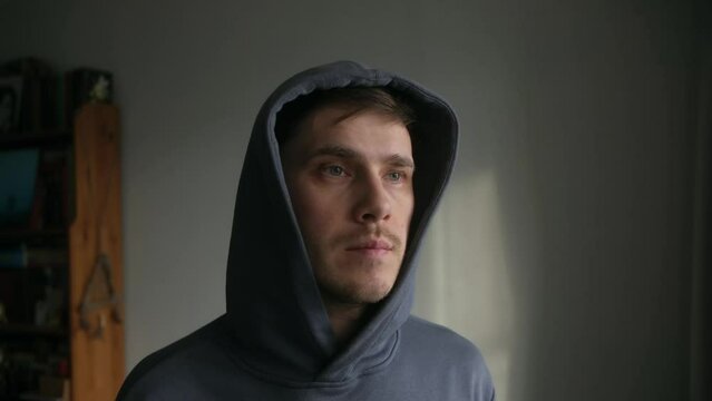 A young man puts a hood on his head at home. Portrait. Slow motion. wear hoodie.