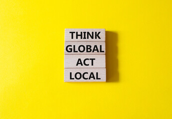 Think global act local symbol. Wooden blocks with words Think global act local. Beautiful yellow background. Business and Think global act local concept. Copy space.