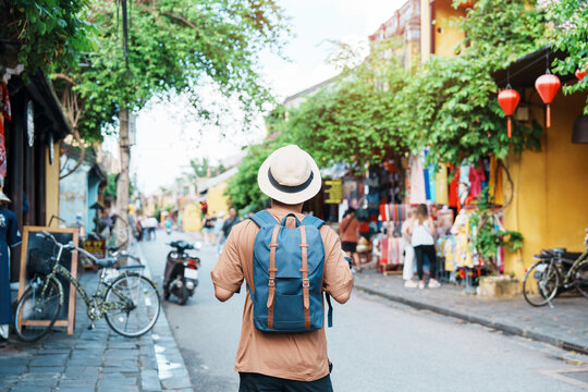 happy Solo traveler sightseeing at Hoi An ancient town in central Vietnam, man traveling with backpack and hat. landmark and popular for tourist attractions. Vietnam and Southeast Asia travel concept