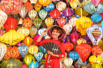 happy woman wearing Ao Dai Vietnamese dress with colorful lanterns, traveler sightseeing at Hoi An ancient town in central Vietnam.landmark for tourist attractions.Vietnam and Southeast travel concept