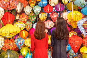 Couple women wearing Ao Dai Vietnamese dress with colorful lantern, traveler sightseeing at Hoi An ancient town in central Vietnam.landmark for tourist attractions.Vietnam and Southeast travel concept