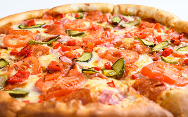 Closeup surface of pizza with vegetables and ham. Selective focus in the center of the frame. Pizza with cucumbers and peppers