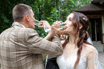 The bride and groom drink champagne at the wedding.
