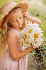 a beautiful blonde girl in a straw hat with white daisies in her hands