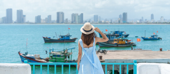 Woman traveler visiting at Son Tra marina. Tourist with blue dress and hat traveling in Da Nang city. Vietnam and Southeast Asia travel concept © Jo Panuwat D