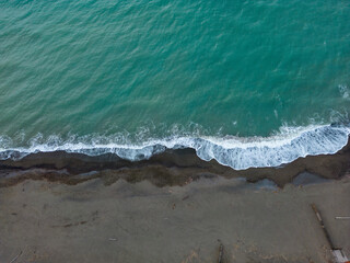 Aerial view of dark beach with small waves splashing