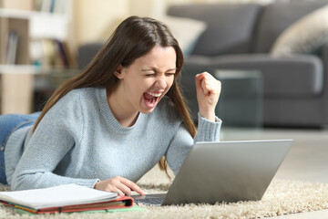 Excited student checking laptop at home