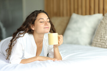 Woman on a bed enjoying a cup of coffee