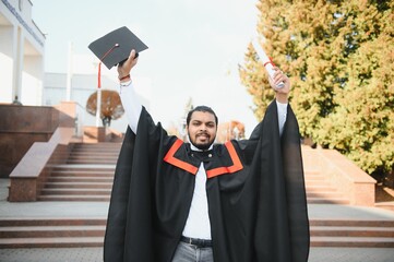 portrait of successful indian student in graduation gown.