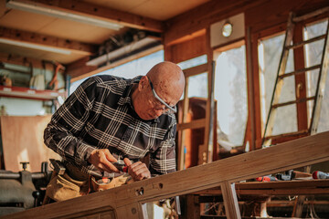 Senior carpenter using chisel in workshop