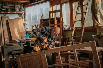 Senior carpenter using chisel in workshop