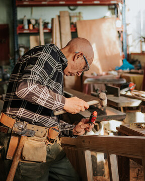 Senior carpenter using chisel and hammer in workshop