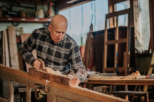 Senior carpenter using jointer in workshop