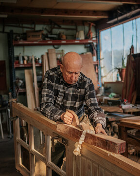 Senior carpenter using jointer in workshop