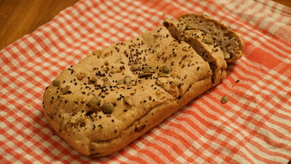 gluten-free bread with sesames and black cumin on the table with a red and white kitchen cloth