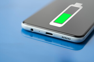 Charging a mobile smartphone on a blue glossy background