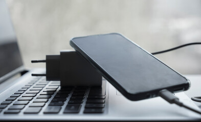 The smartphone is connected to the laptop via USB cable. Smart cell phone being charged.  power...