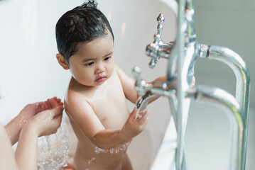 Asian cute kid girl toddler having a bath wash hair cleaning bathing bath tub with her mother....