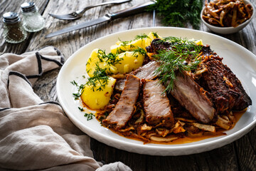 Tasty roast ribs with boiled potatoes on wooden table
