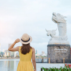 Fototapeta premium Woman Traveler with yellow dress visiting in Da Nang. Tourist sightseeing the river view with Carp Dragon Statue or Ca Chep Hoa Rong.Landmark and popular. Vietnam and Southeast Asia travel concept