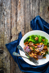Marinated herrings with delicacies, walnuts and fresh vegetable leaves on wooden table
