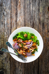 Marinated herrings with delicacies, walnuts and fresh vegetable leaves on wooden table
