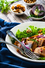 Marinated herrings with delicacies, walnuts and fresh vegetable leaves on wooden table
