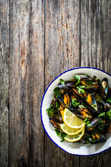 Cooked mussels with lemon and parsley on wooden table
