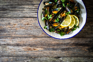 Cooked mussels with lemon and parsley on wooden table
