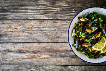 Cooked mussels with lemon and parsley on wooden table
