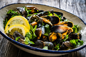 Fototapeta na wymiar Cooked mussels with lemon and parsley on wooden table 