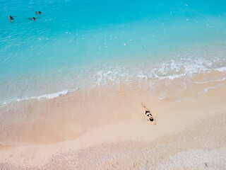 Fototapeta na wymiar overhead view of woman in black swimsuit sunbathing at sea shore