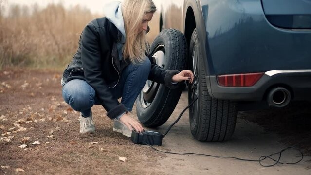 woman using electric tire inflator for pumping flat tire .