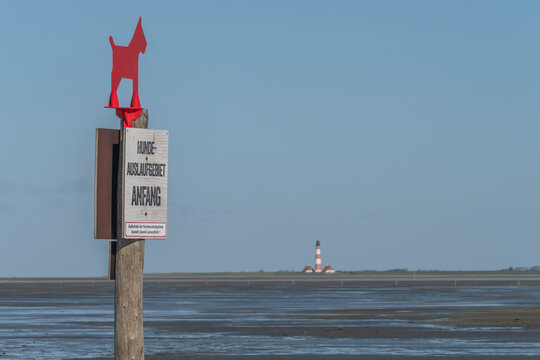 Germany, Schleswig-Holstein, St. Peter-Ording, No dogs allowed sign with Westerheversand Lighthouse in background