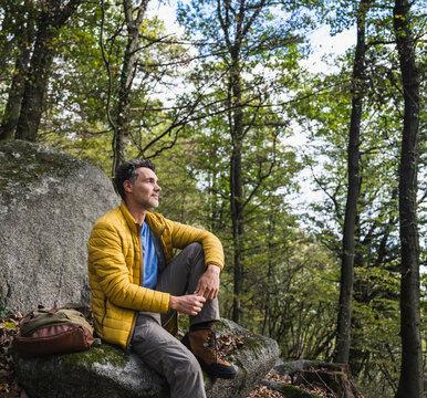 Man with backpack sitting on rock in forest