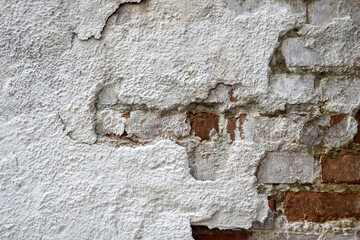 Texture of old brick wall with collapsed plaster. Background of shabby building surface. Destroyed concrete and brick wall with fallen plaster. Weathered surface. Copy space. Selective focus.