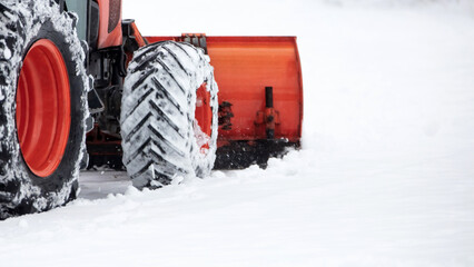 Tractor cleaning urban park paths on a cold snowy day.