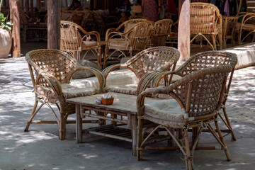 Wooden chairs in the outside garden. Set of luxury wooden garden furniture . Summer concept. Secluded tables with comfortable chairs under among green vegetation. Garden with cozy wicker furniture.