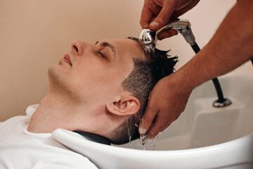 Barber washing hair of caucasian man , close-up