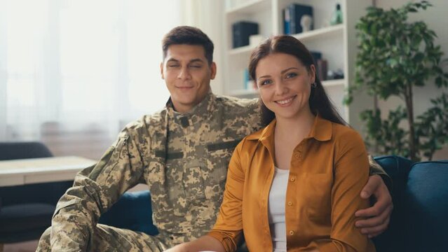 Portrait of young military man and his wife embraced in their home, happy family