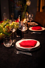 Dinner setting. Glassware ready on a festively dressed dinner table. Red napkins, dark tablecloth, silverware.