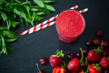 Top down view of berry juice or smoothie with fresh strawberries and cherries on black table. © ZaStock