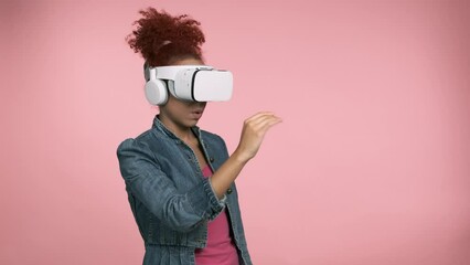 Woman experiencing virtual reality with VR glasses. Young lady wearing vr headset white goggles watching playing looking posing on pink isolated background. Metaverse, innovation, virtual reality