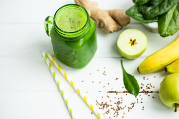 Mason jar mug filled with green smoothie and ingredients on wooden table. clean eating concept. 