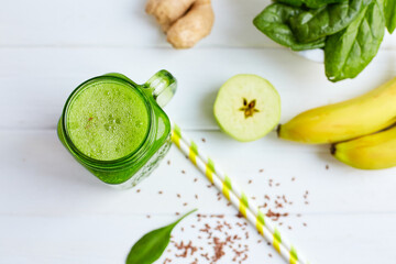 From above shot of jar mug filled with green smoothie and ingredients on wooden table. Healthy food 