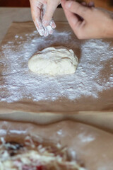 Cooking dough for pizza. The cook rolls out the dough and sips the flour