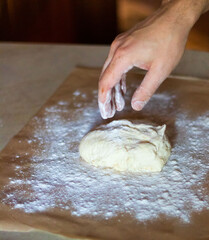Cooking dough for pizza. The cook rolls out the dough and sips the flour